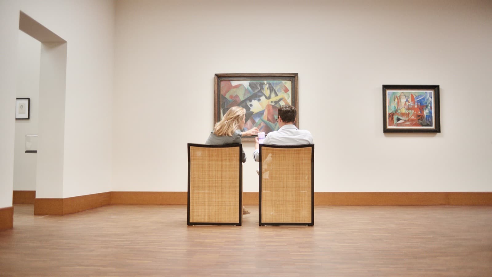 Zwei Besucher sitzen vor Gemälden in einem Saal des Franz Marc Museums